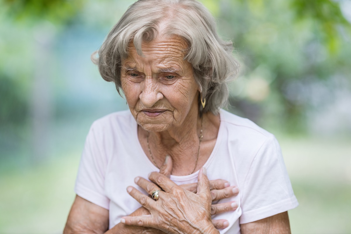 Elderly woman outdoors with heart pain holding her chest