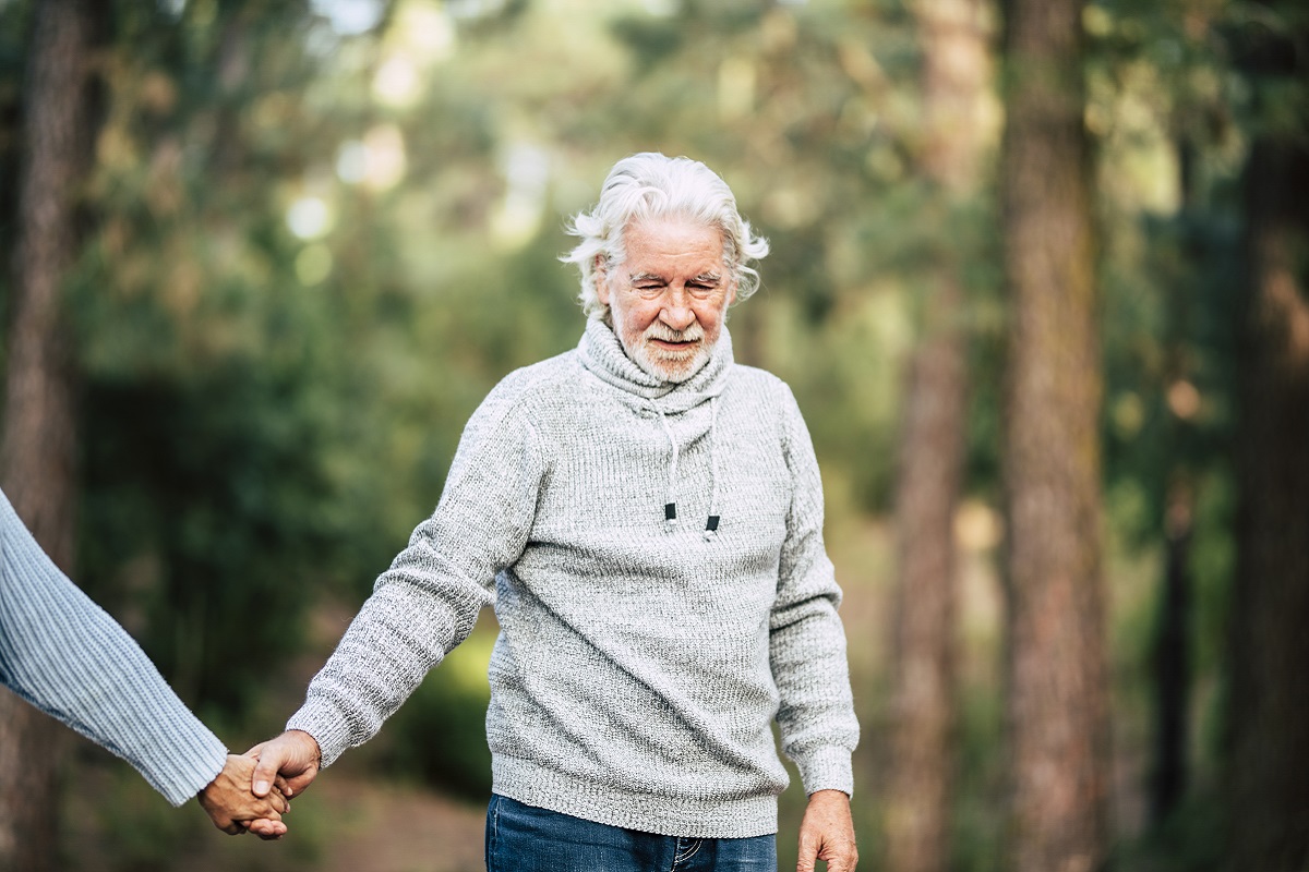 Assistance and disease alzheimer problems for old people- senior man holding hands and walk in the forest to enjoy the outdoor nature leisure activity