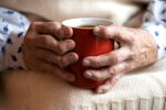 Kobieta chora na reumatyzm trzyma w dłoniach kubek z herbatą