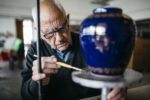 Senior wykorzystuje swój czas wolny na dekorowanie ceramicznego wazonu