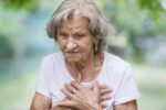 Starsza kobieta z bólem serca trzymająca klatkę piersiową